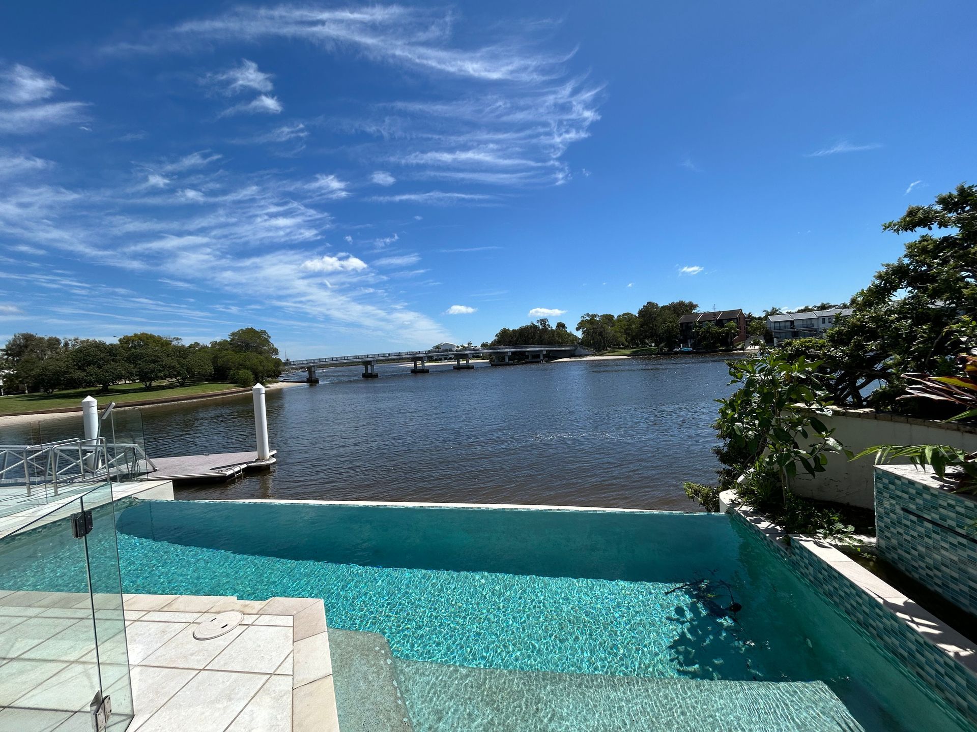 Infinity Pool Overlooking a River With a Bridge Under a Bright Blue Sky — Bromage Pool Heating in Coolum, QLD
