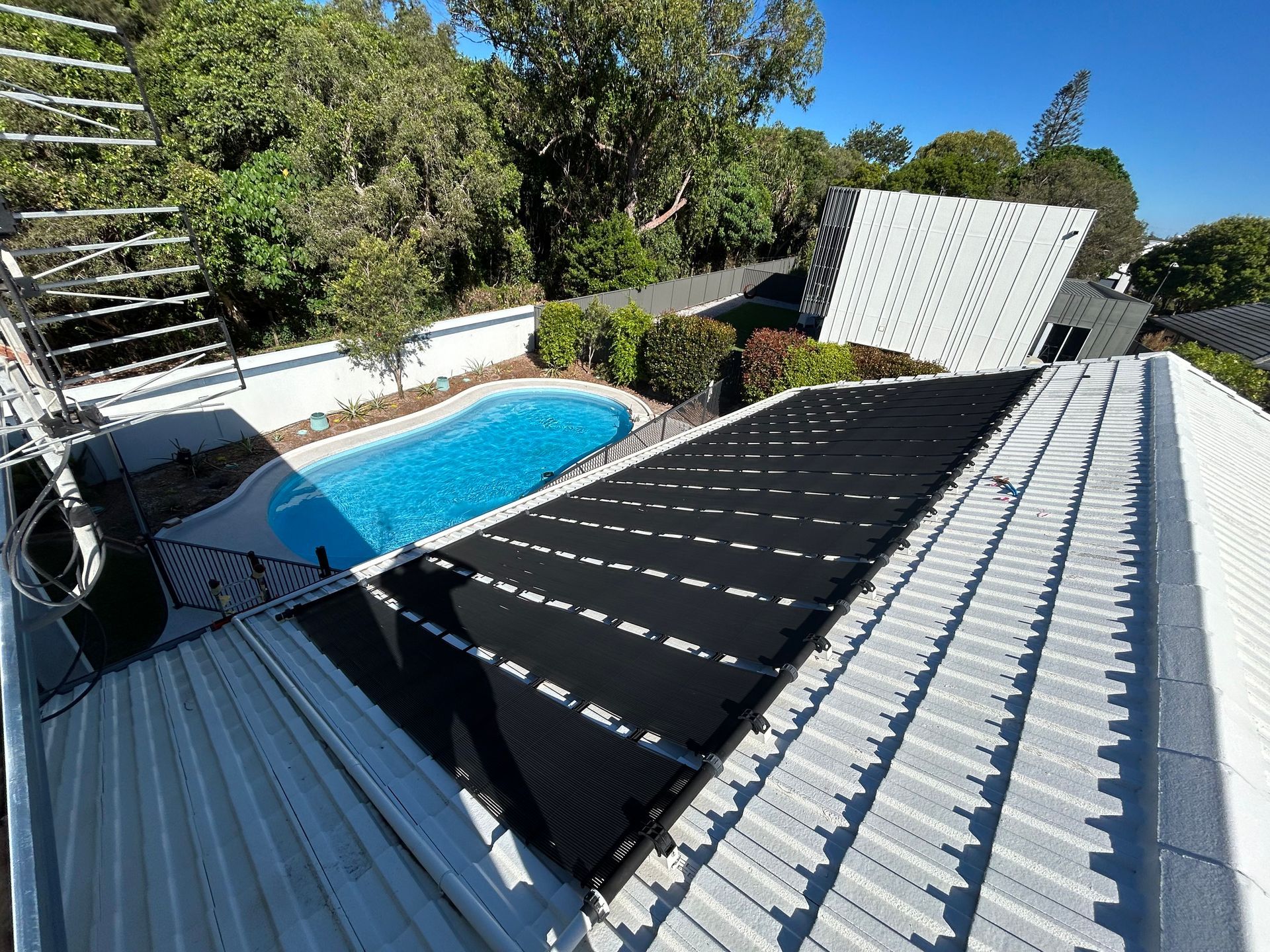 Backyard Pool Beside a Black Shade Canopy and Corrugated Rooftops Under a Sunny Blue Sky — Bromage Pool Heating in Buderim, QLD