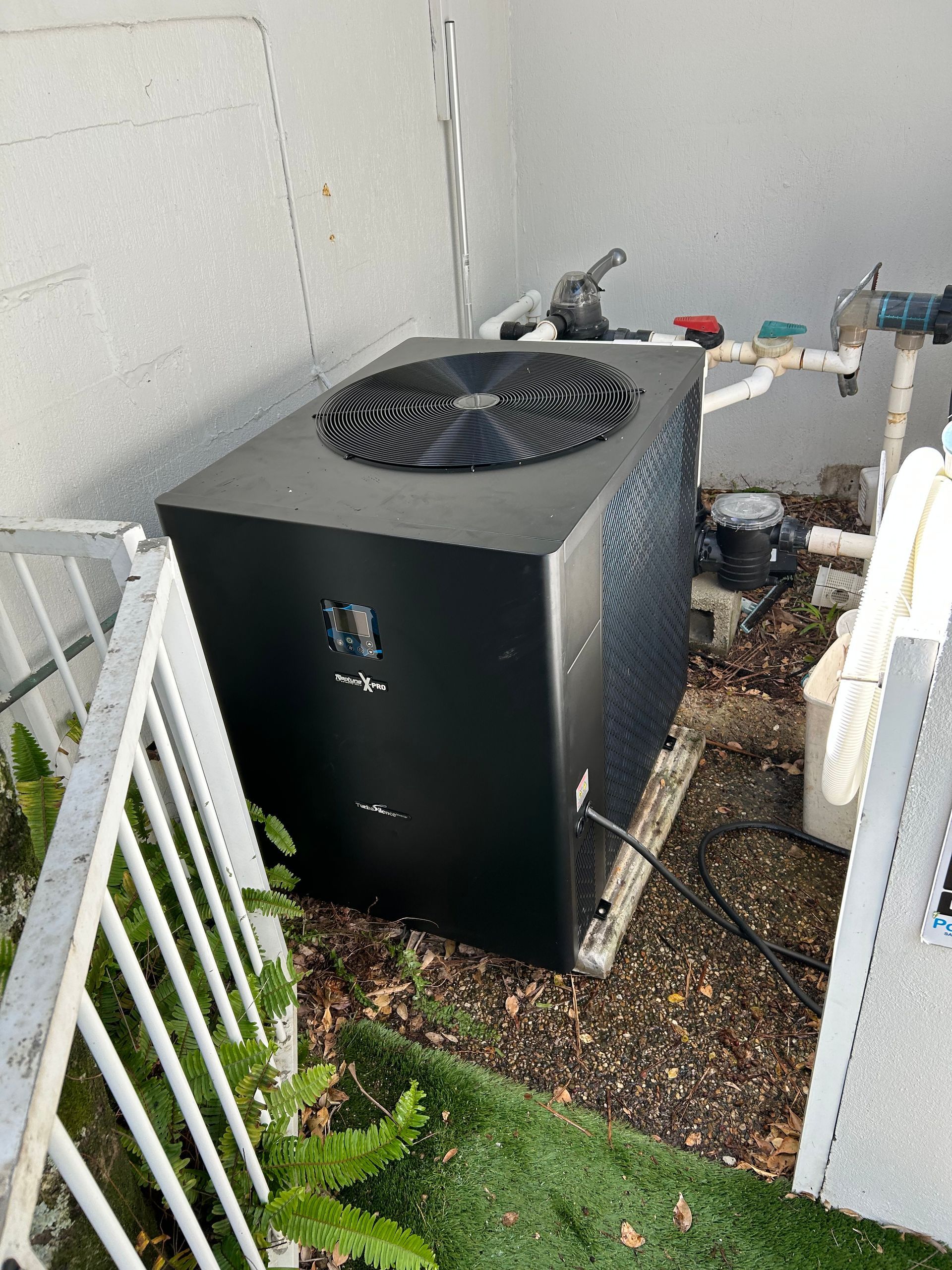 Black Hvac Unit With Fan on Top Beside a House Wall in a Narrow Outdoor Utility Area — Bromage Pool Heating in Yandina, QLD