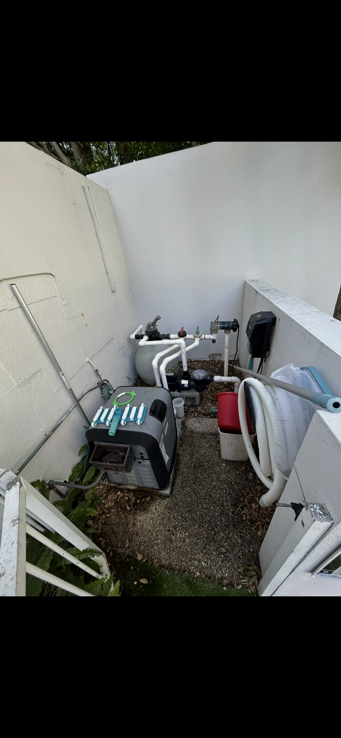 Cluttered Outdoor Storage Area With Scattered Tools, Equipment, and Debris Beside a White Wall and Fence — Bromage Pool Heating in Maleny, QLD