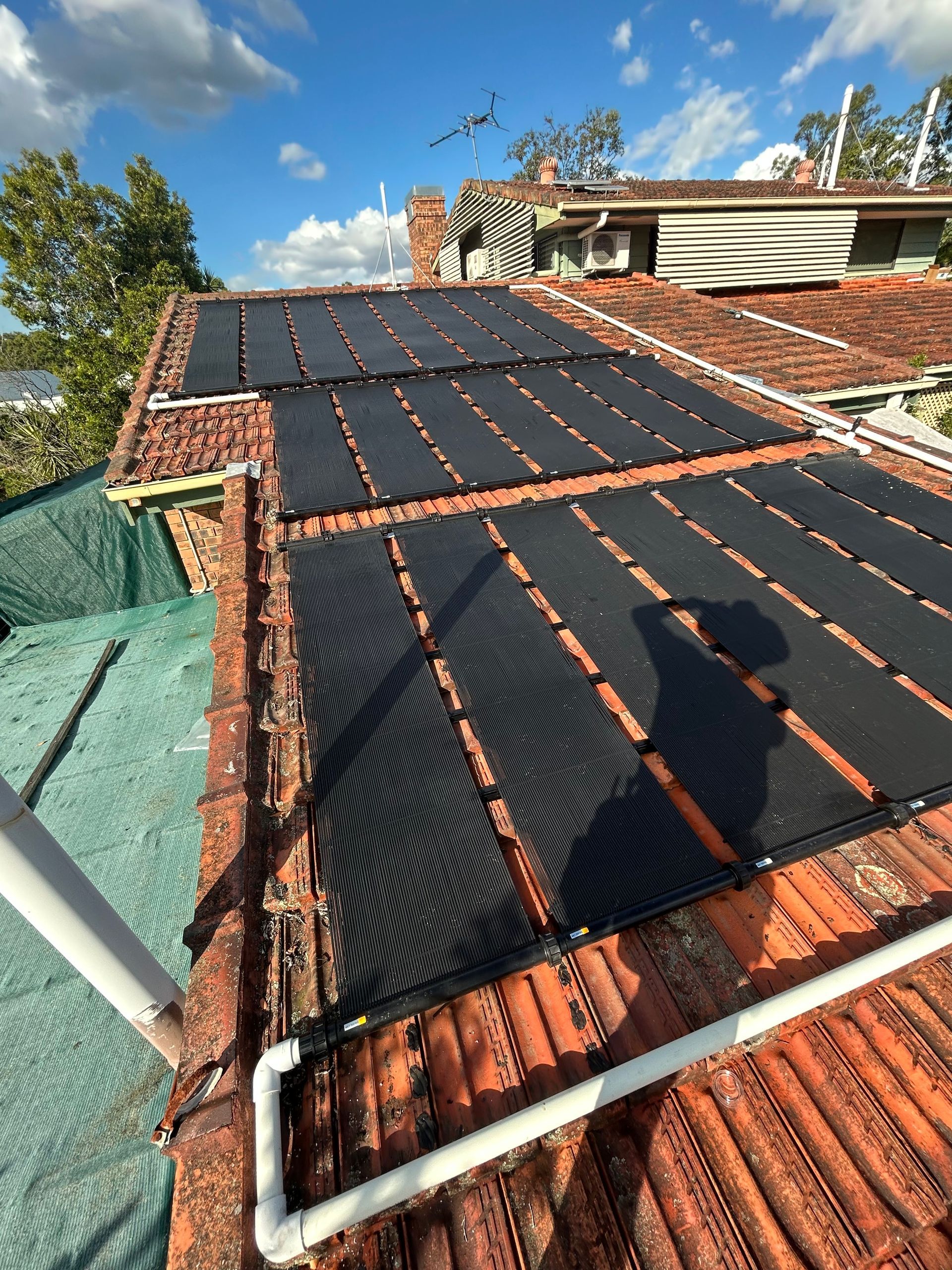 Solar Panels Mounted on a Red-tiled Roof Under a Blue Sky — Bromage Pool Heating in Nambour, QLD