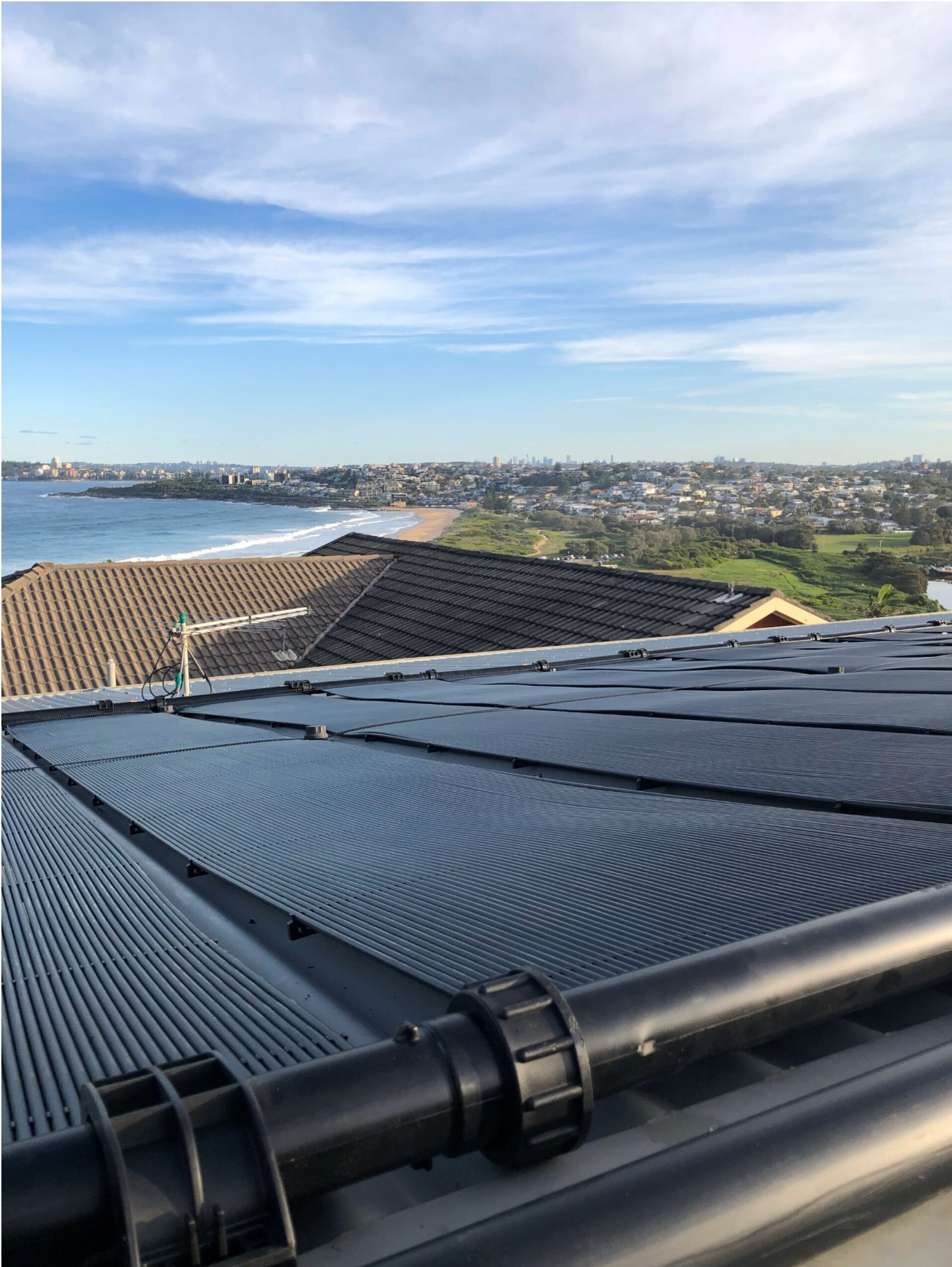 Rooftop Solar Panels Overlooking a Coastal Neighborhood and Blue Sky Over the Water — Bromage Pool Heating in Yandina, QLD
