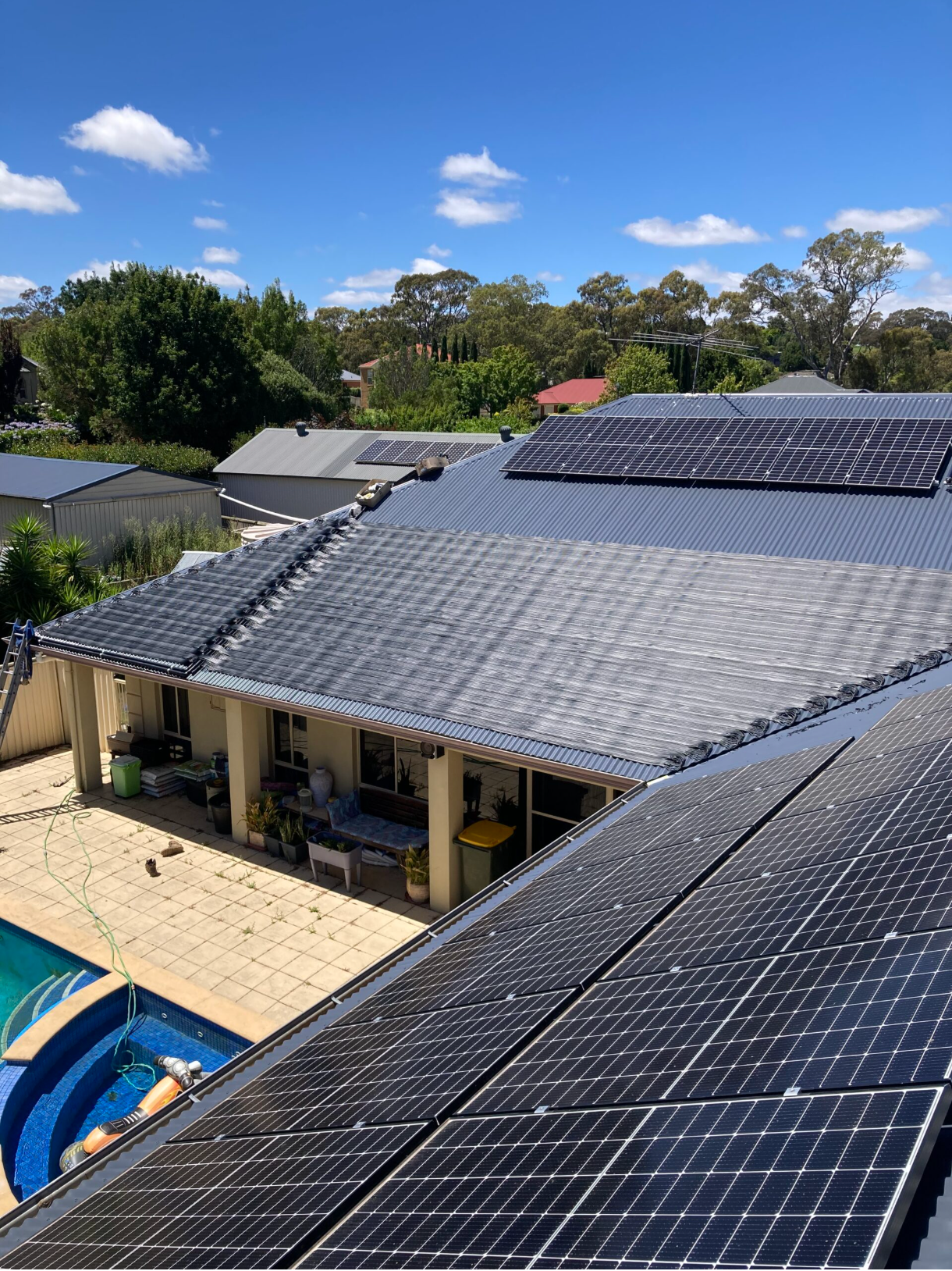 Suburban House With Solar Panels on Roof Beside a Pool Under a Clear Blue Sky — Bromage Pool Heating in Noosa, QLD
