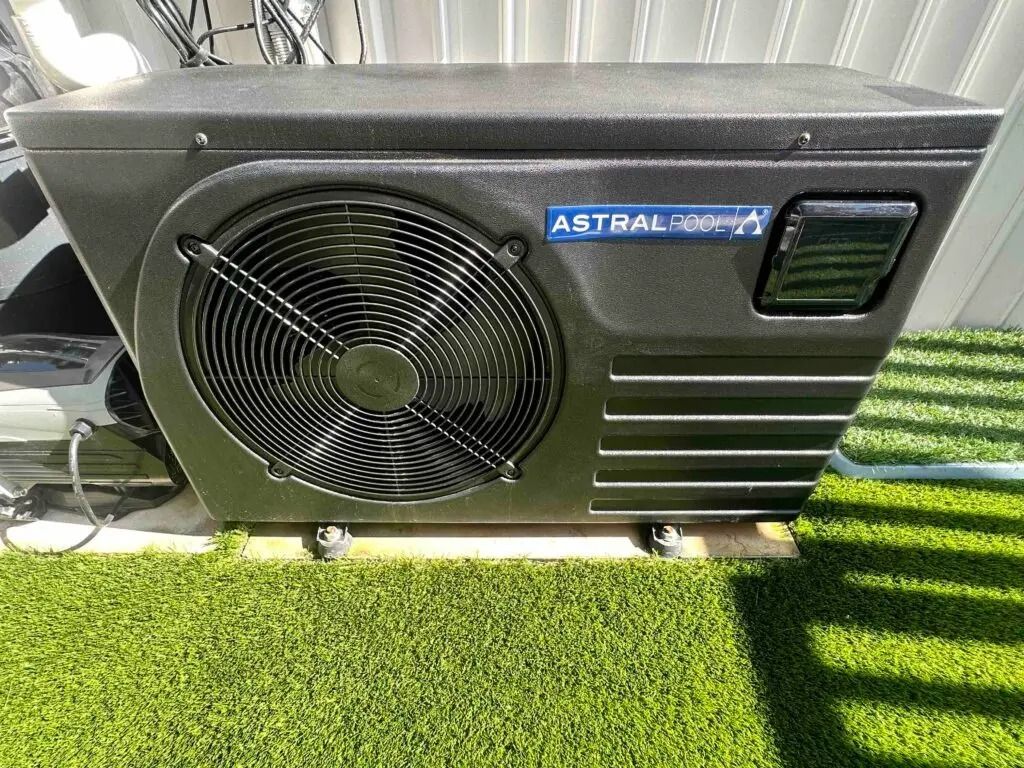 Black Outdoor Hvac Unit With Large Fan and Vents Sitting on Grass Near a Building — Bromage Pool Heating in Noosa, QLD