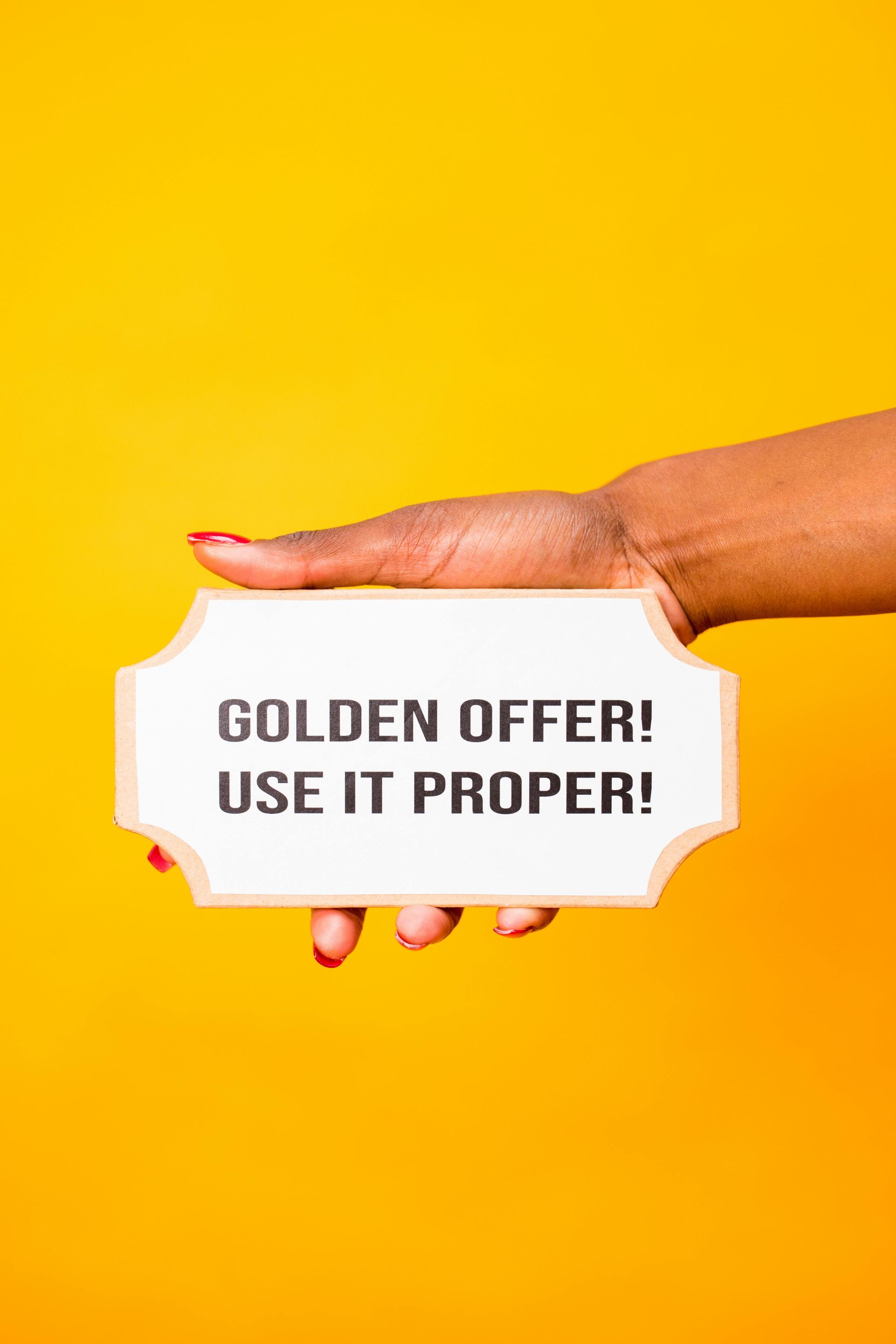Hand holding golden offer sign on yellow background — digital marketing Alaska promotions graphic