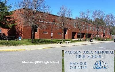 A sign for madison area memorial high school is in front of a large brick building.