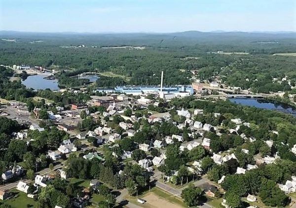 An aerial view of a small town surrounded by trees and a river
