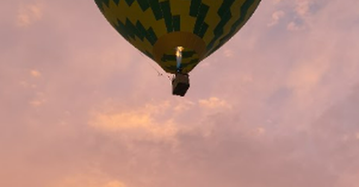 A from-the-ground view shows a yellow and green hot air balloon floating during a sunset. The sky is purple and orange.