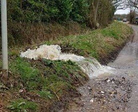 A stream of water is running down the side of a road.
