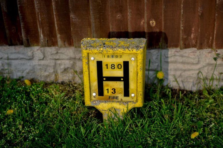 A yellow sign with the letter h on it is sitting in the grass.
