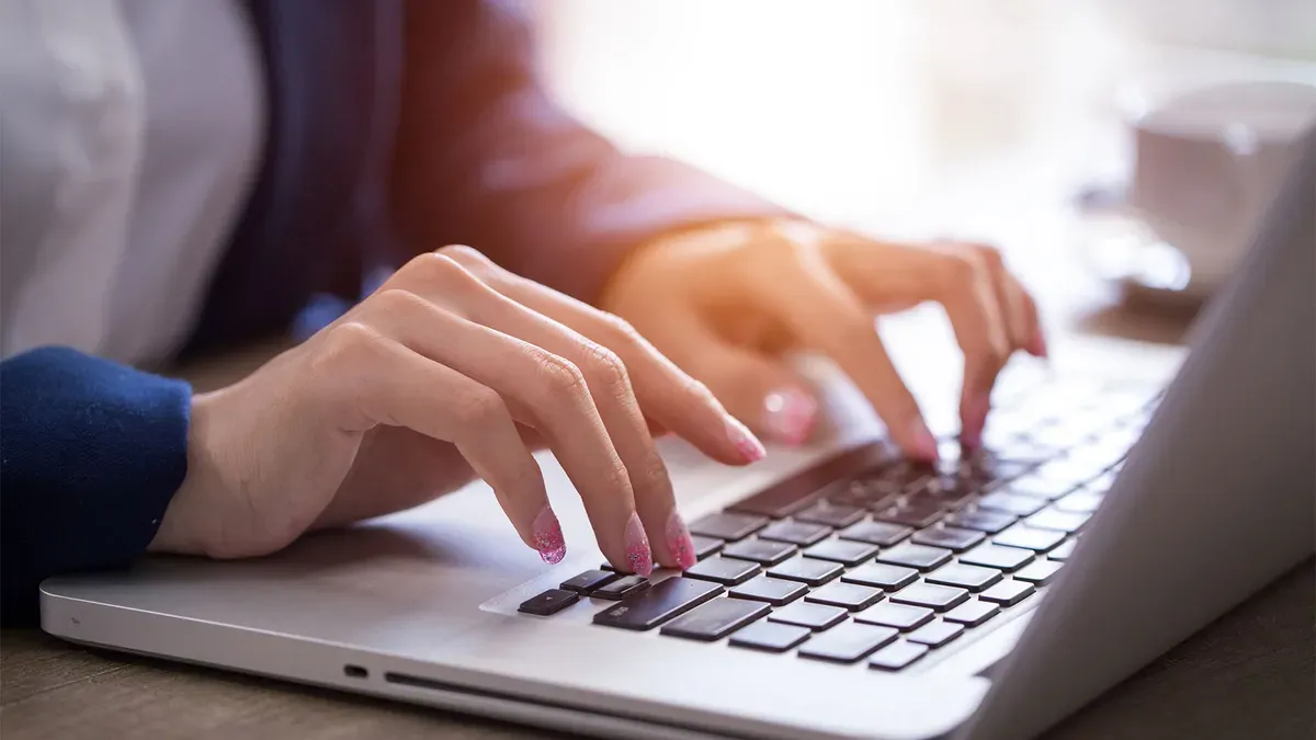A woman is typing on a laptop computer.