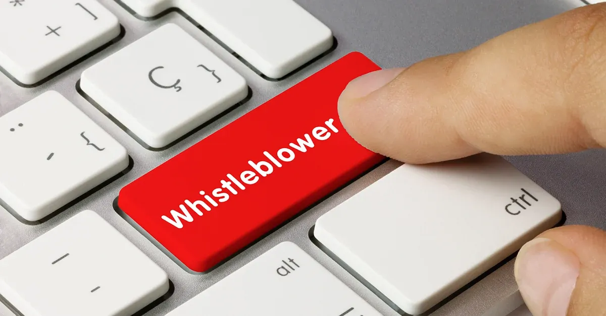A person is pressing a red button on a keyboard that says whistleblower