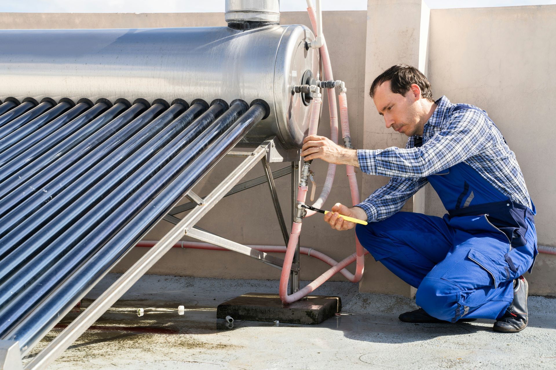 A man is working on a solar water heater on a roof.