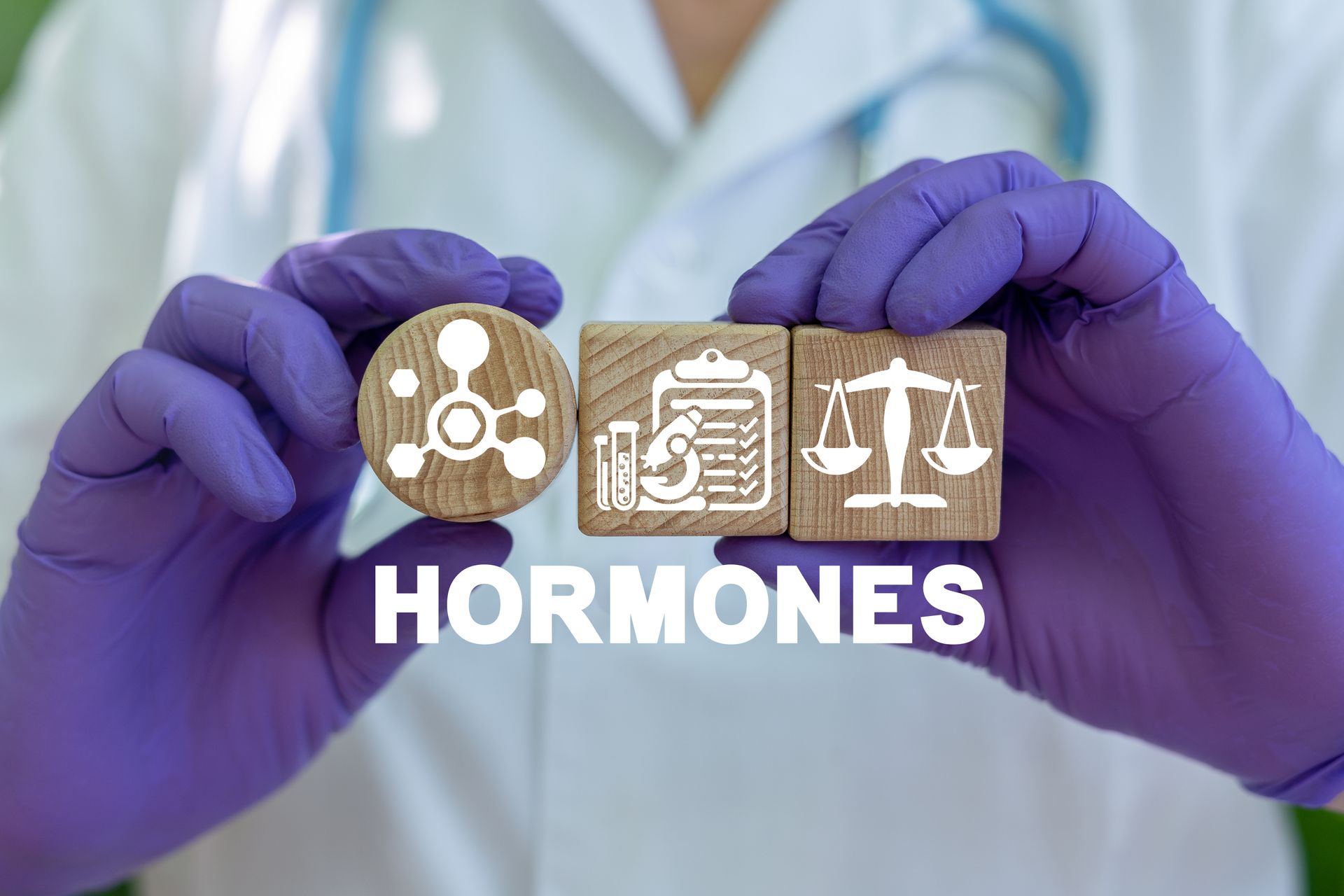 A person wearing purple medical gloves holding three wooden blocks showing icons of molecules, a lab report, and a scale.