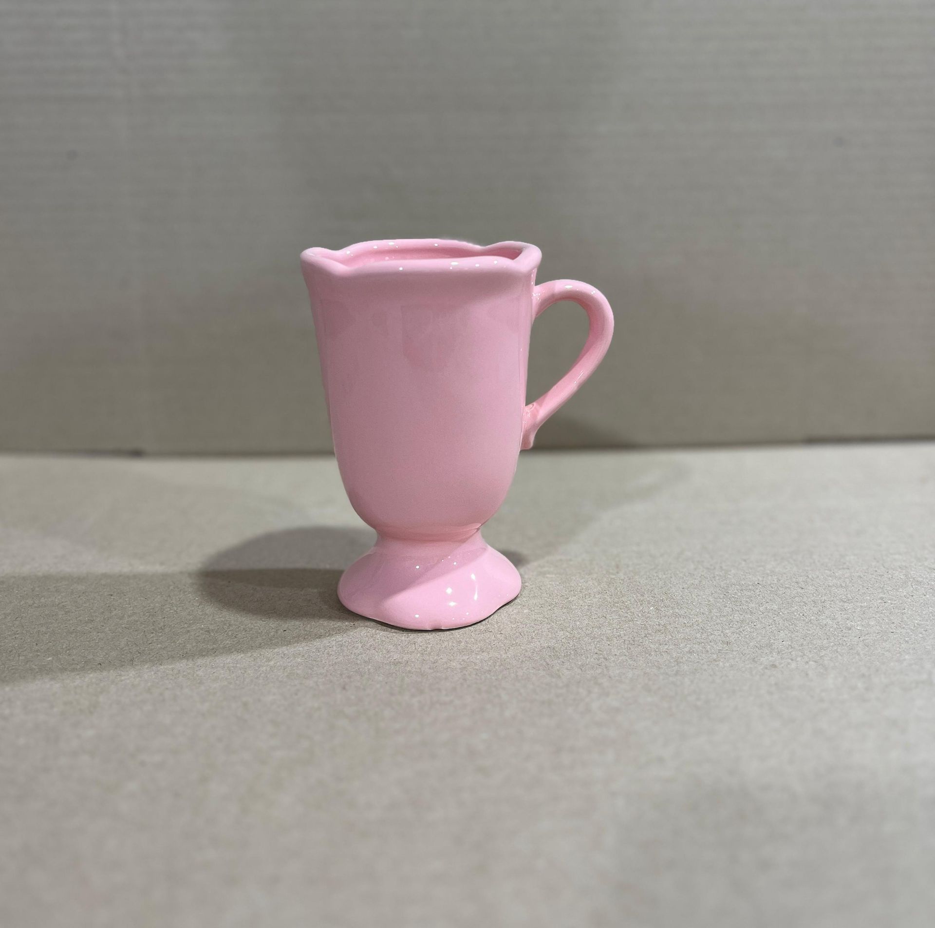 Taza con pedestal blanco y borde festoneado.