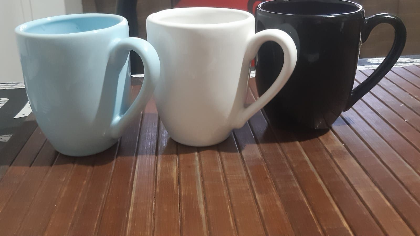 Taza blanca sobre un mantel de madera, sobre una superficie roja y blanca.