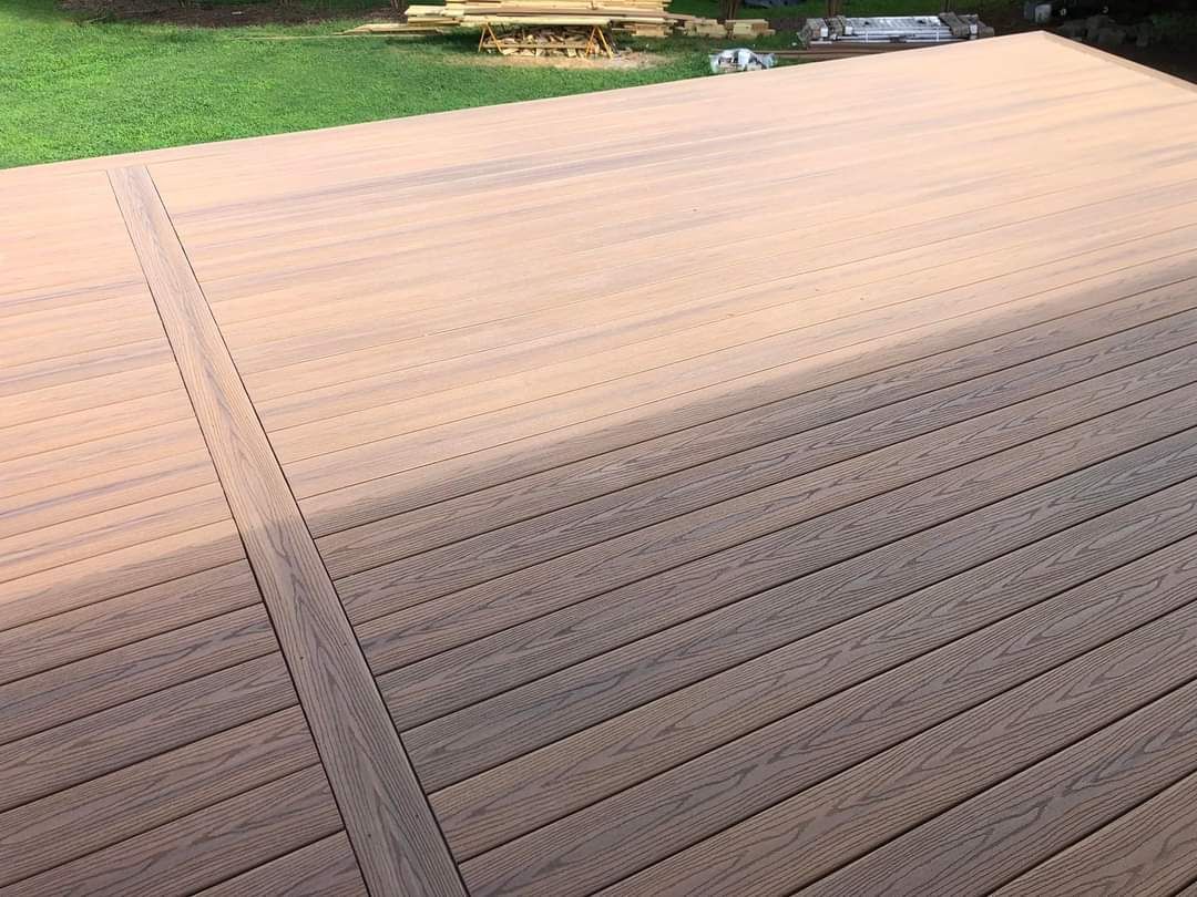 A wooden deck surface showing a clear transition from a dark-stained area to a light, unrefined section.