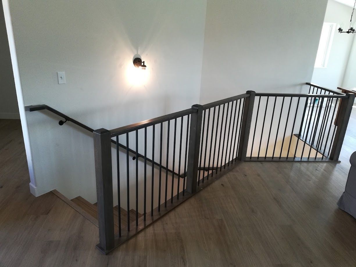 Indoor wooden staircase with dark metal railings and balusters leading to an upper landing.