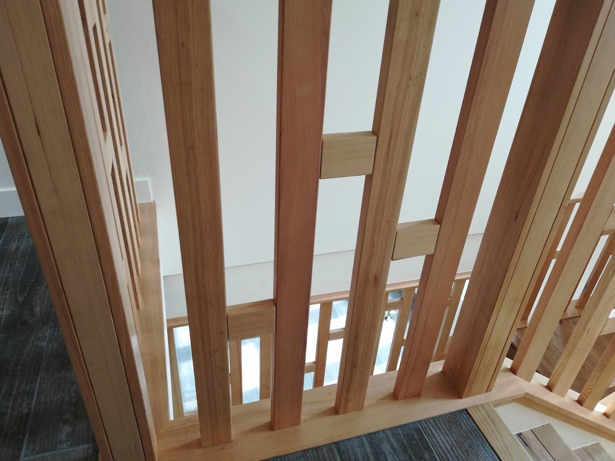 Wooden staircase railing with vertical balusters and decorative horizontal cross-bracing elements in a home setting.