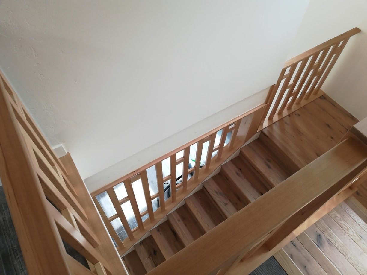 High-angle view of a wooden staircase with a matching railing and balustrade leading down to a lower floor.