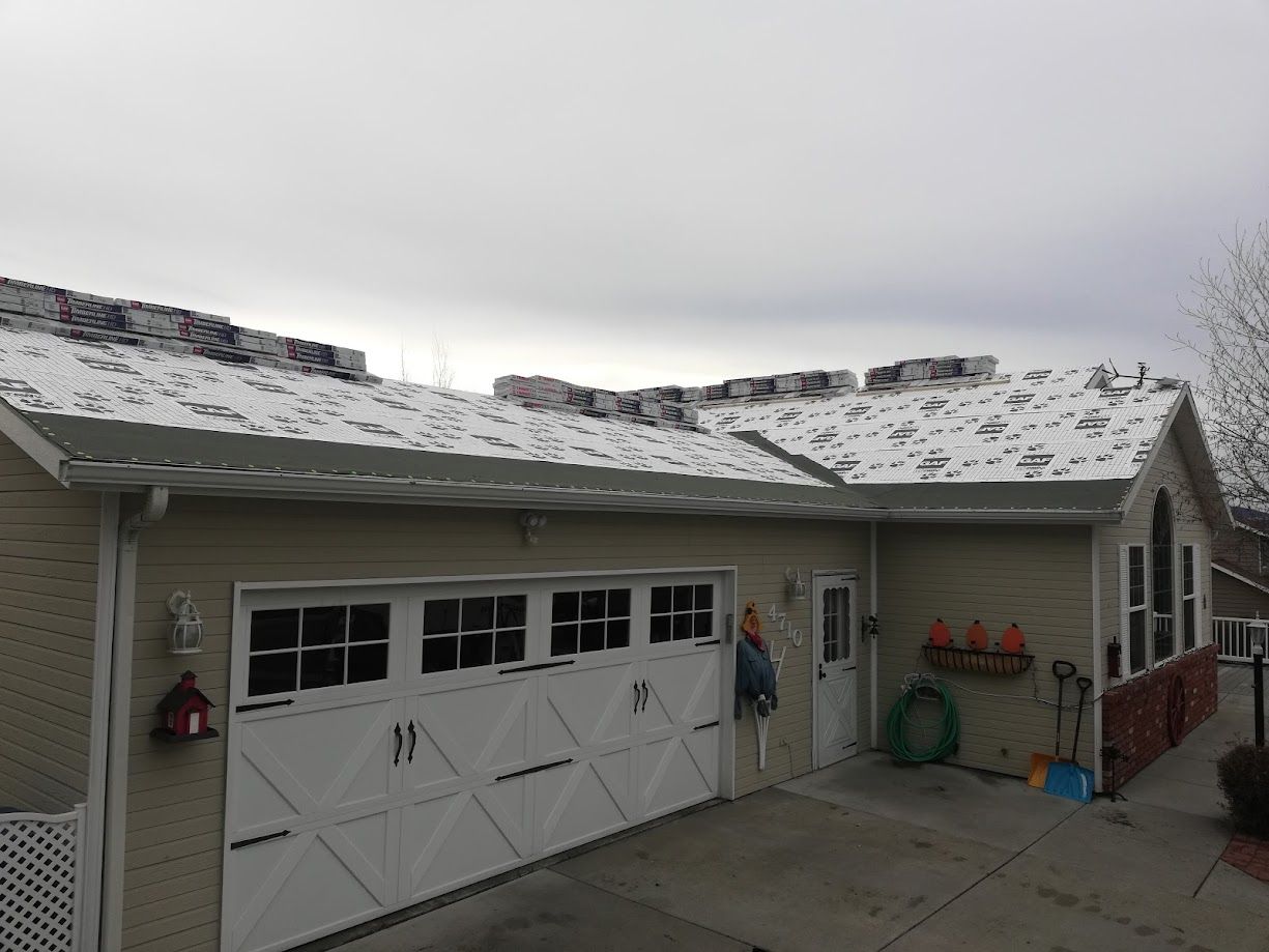 A tan house with a snow-dusted roof, a white garage door, and a partially visible person standing near the side door.