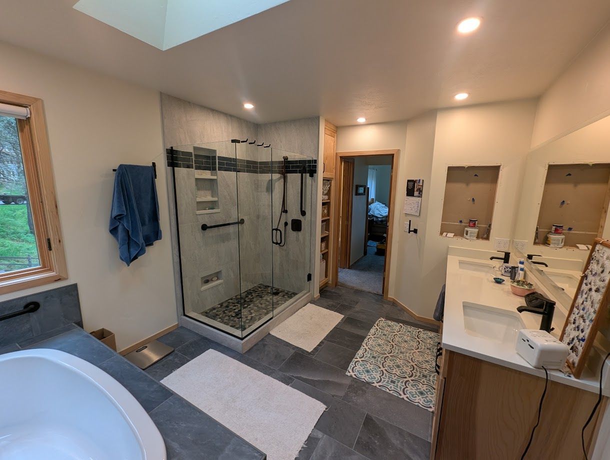 Modern bathroom featuring a glass shower stall, a soaking tub, and a double vanity with grey tile floors.