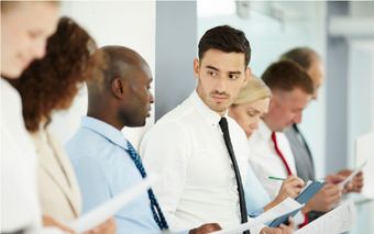 Un grupo de hombres de negocios están parados en una fila mirando papeles.