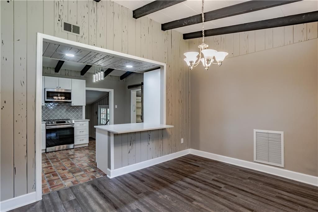 An empty living room with hardwood floors and a chandelier.