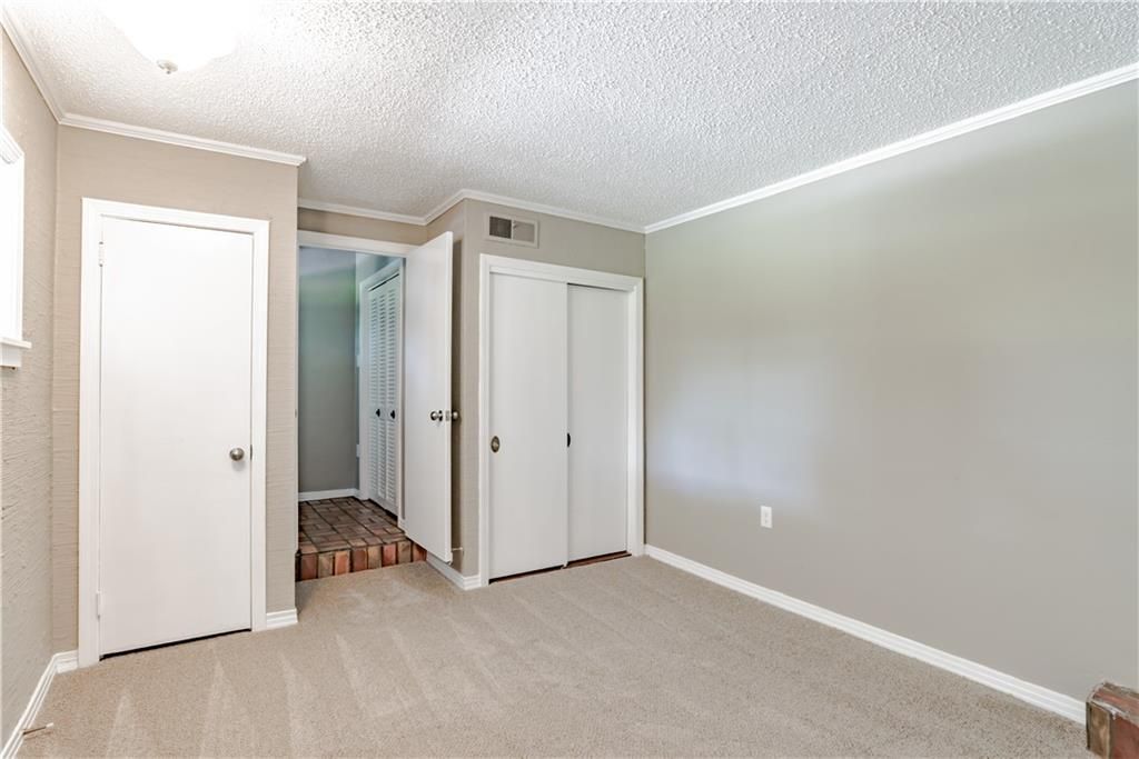 An empty room with a carpeted floor and white doors.