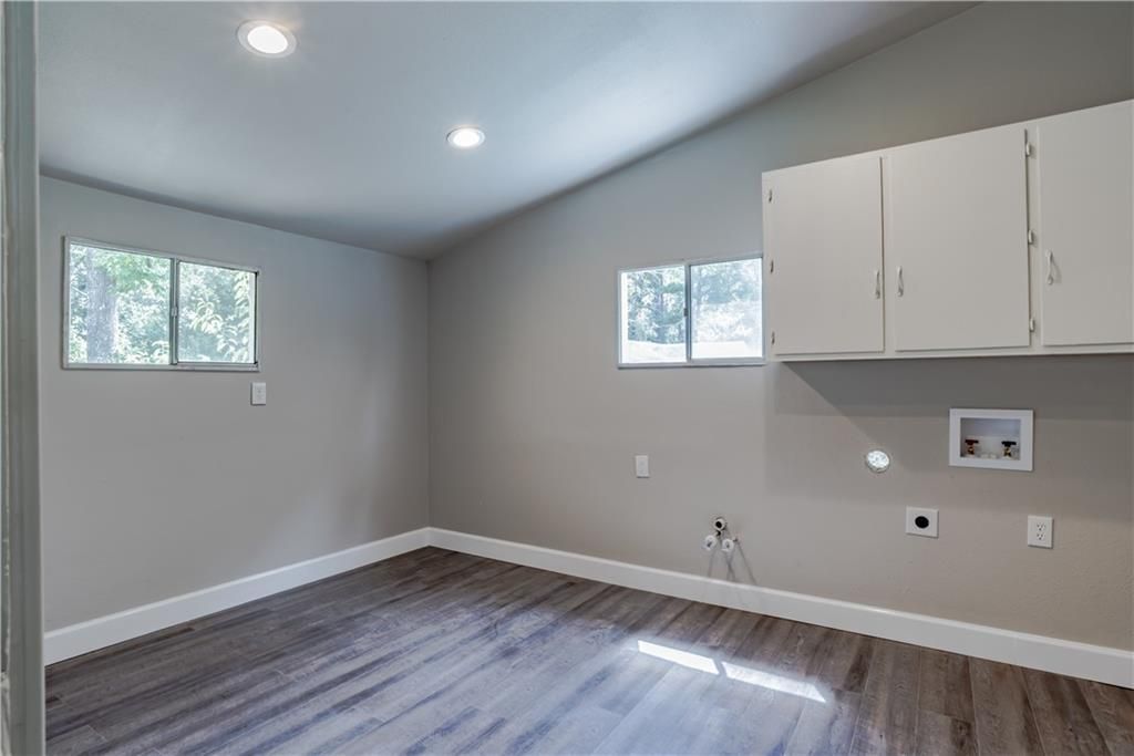 An empty room with hardwood floors and white cabinets.