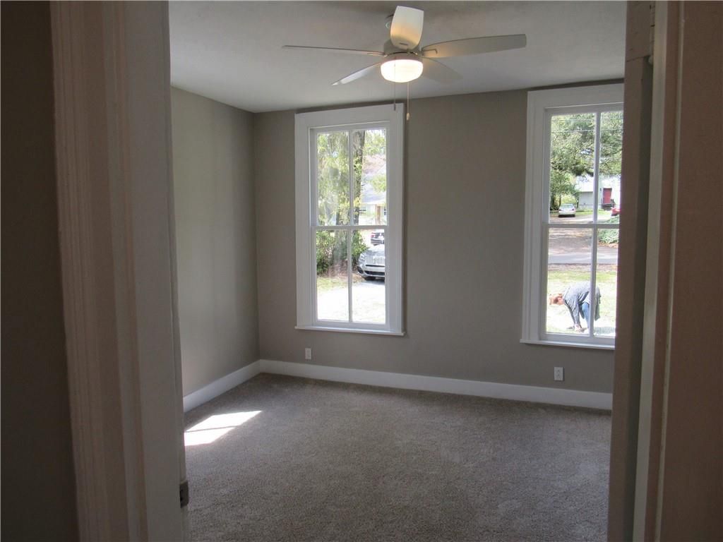 An empty room with a ceiling fan and two windows