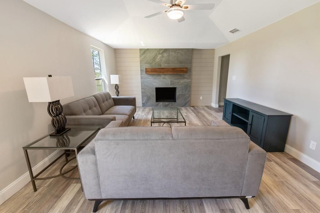 A living room with two couches , a fireplace and a ceiling fan.