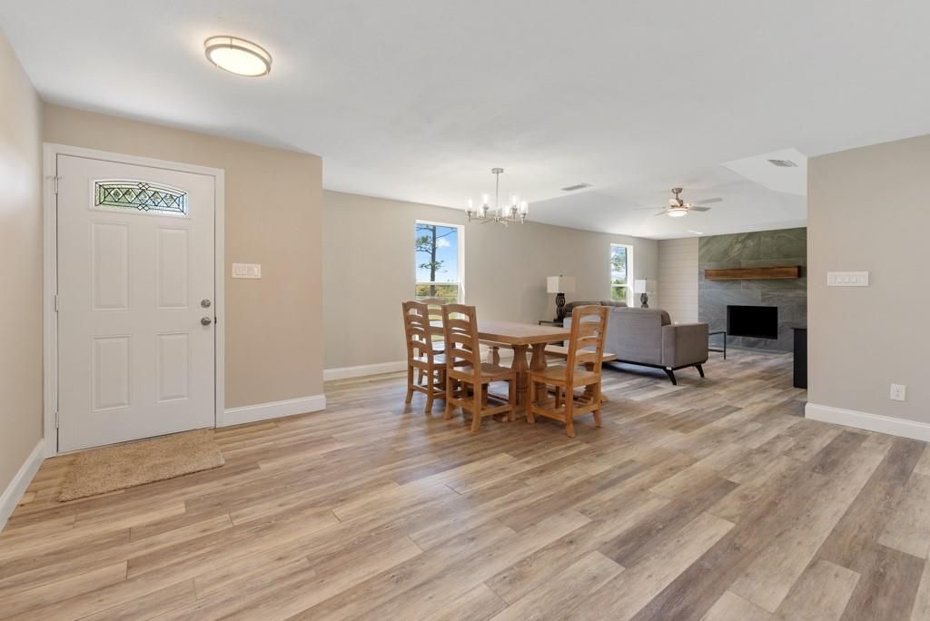 A living room with hardwood floors , a table and chairs , and a fireplace.