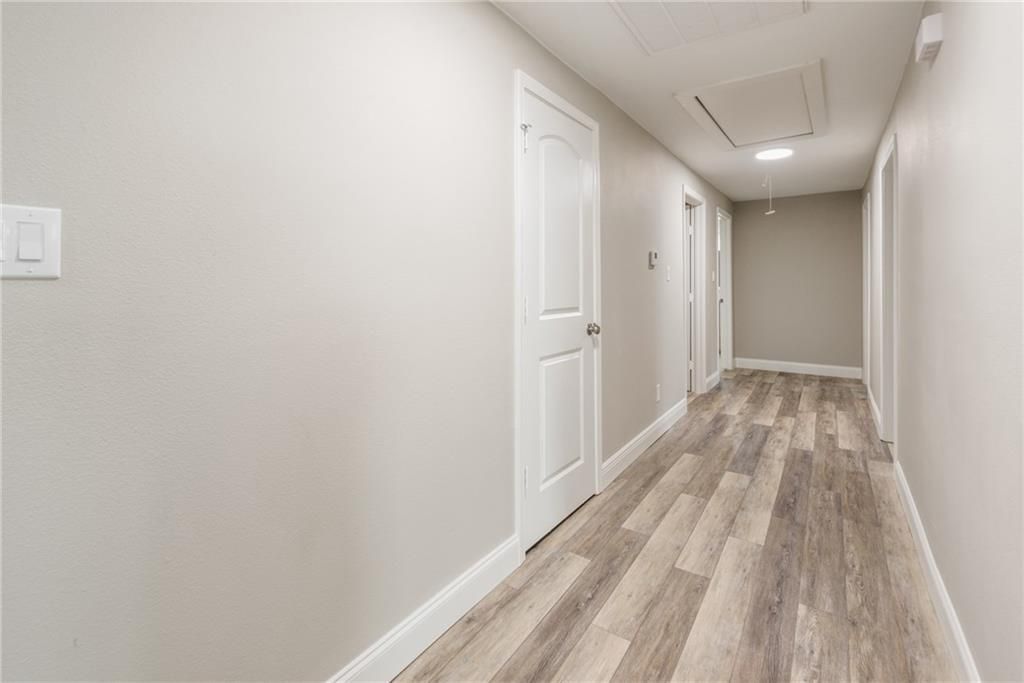 A long hallway with wooden floors and white walls.