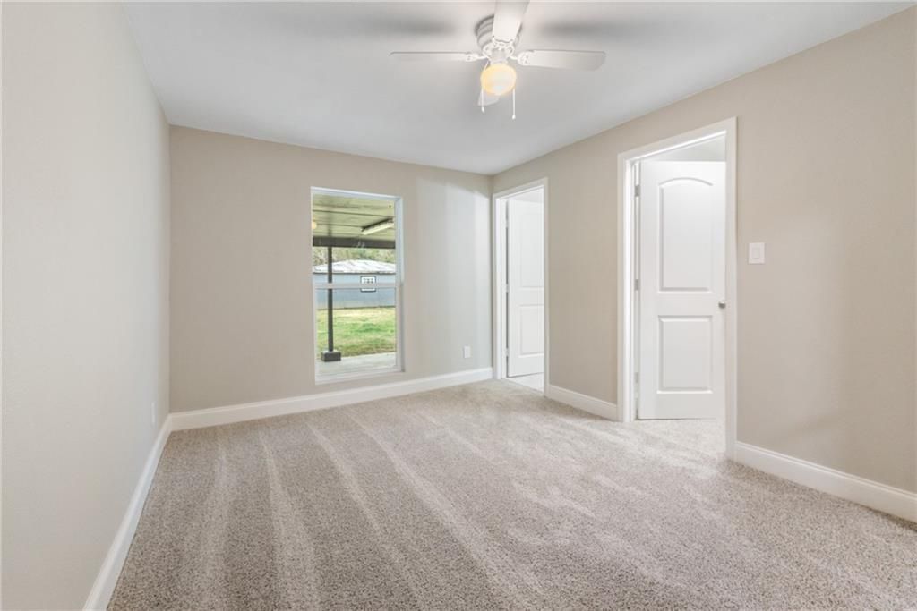 An empty room with a ceiling fan and a window.
