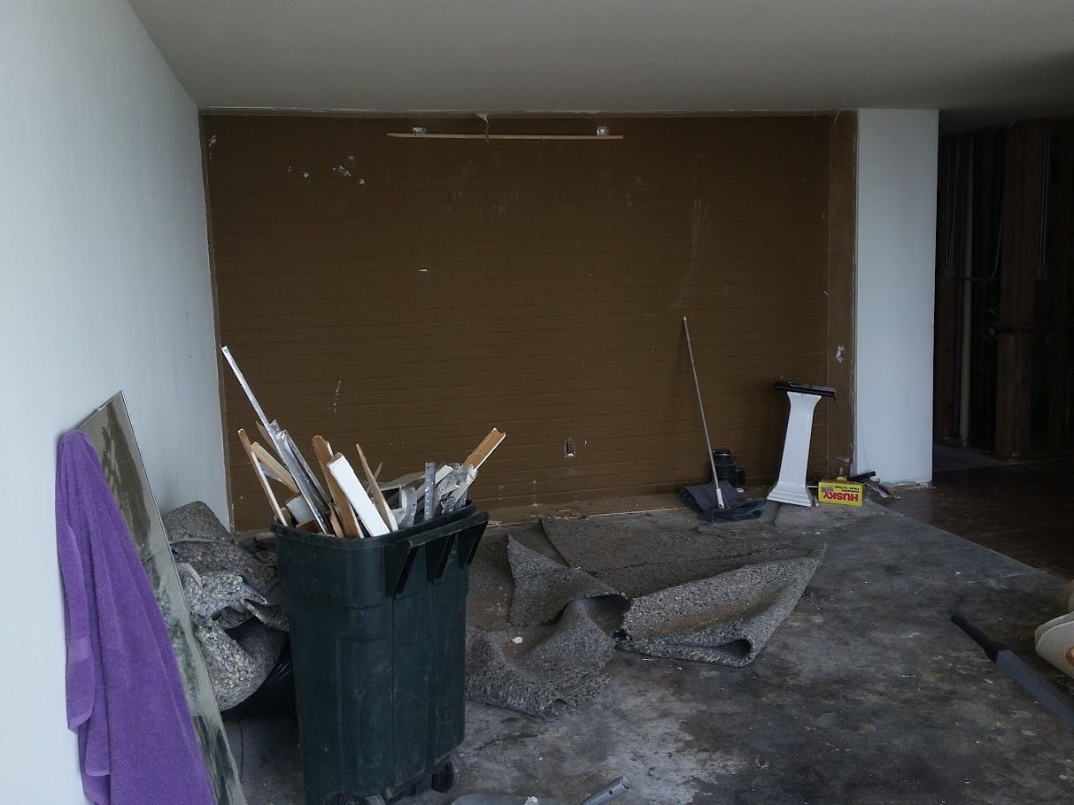 A room with a trash can filled with brushes and a purple towel