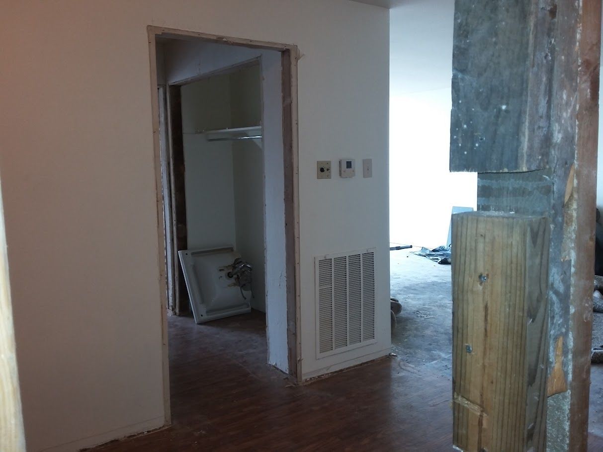 A room with a wooden floor and white walls is being remodeled.