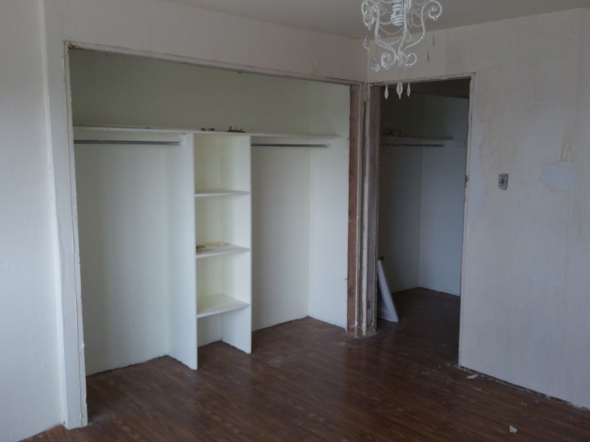 An empty room with a chandelier hanging from the ceiling and a walk in closet.