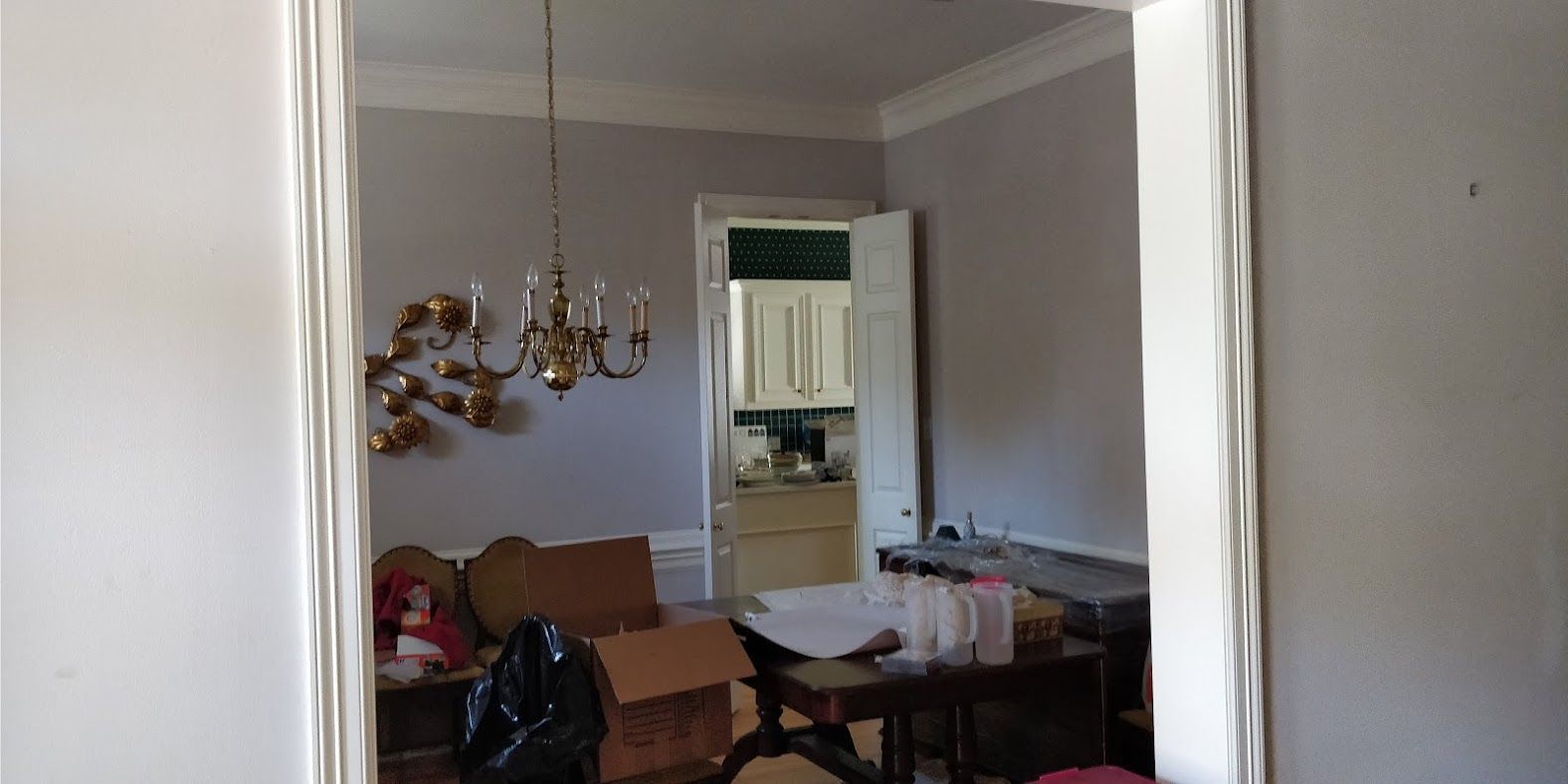 A living room with a large mirror on the wall and a chandelier hanging from the ceiling.