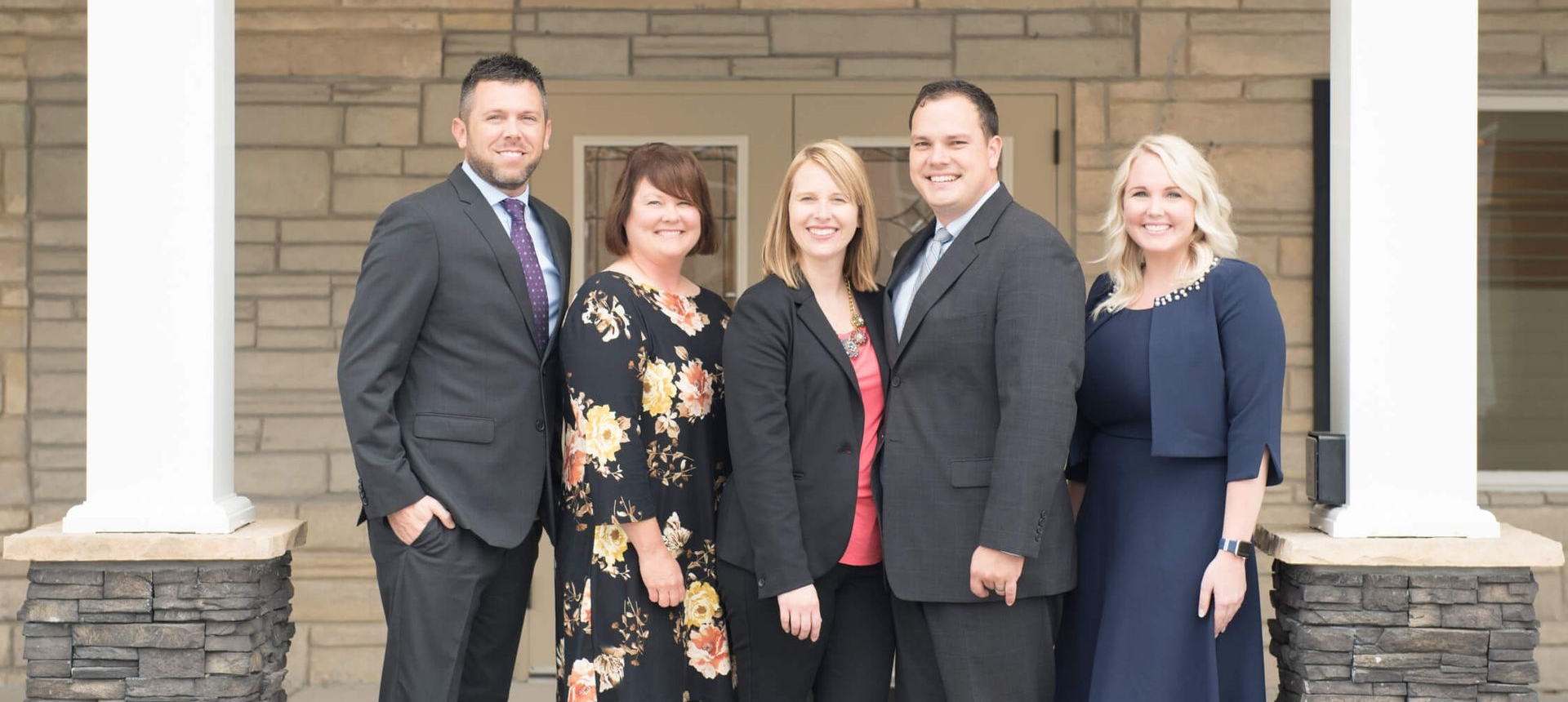 Five people in business attire standing outside a building.