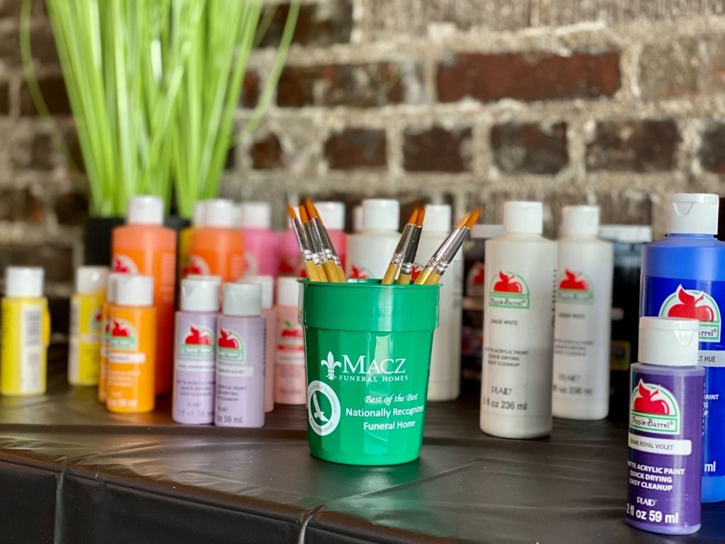 Paint bottles and brushes arranged on a table, with a brick wall background.