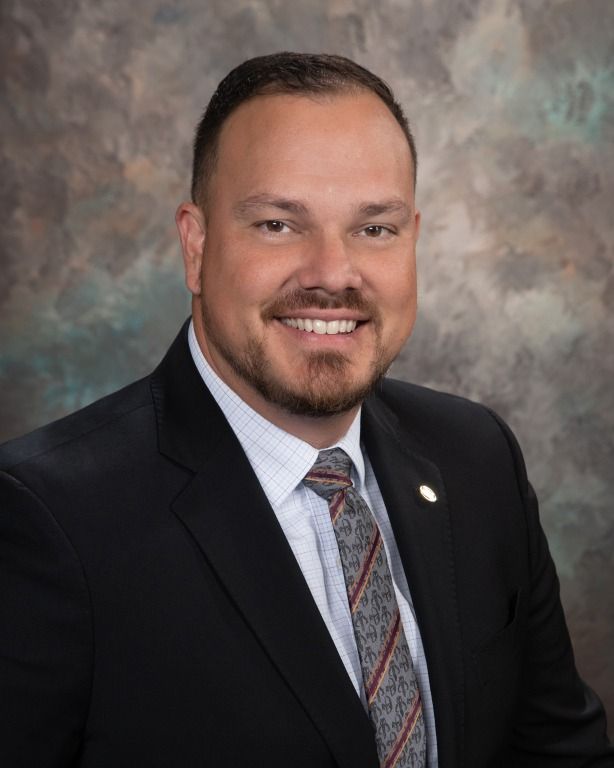 Man in suit smiles at the camera, against a textured background.