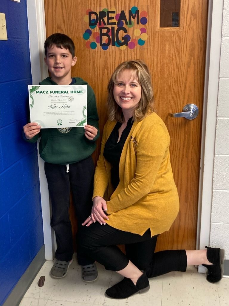 Boy holding certificate with woman in front of 