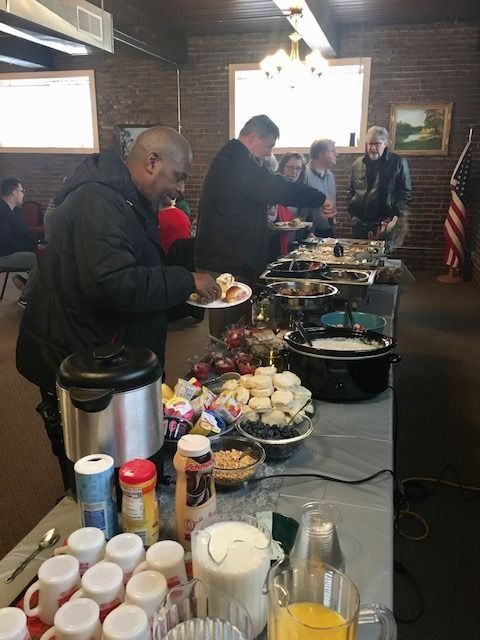 People at a buffet with food and drinks. People are serving themselves at the food line.