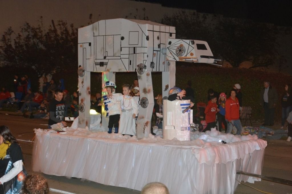 Star Wars AT-AT float in parade; children in costumes; nighttime setting, street, crowd.