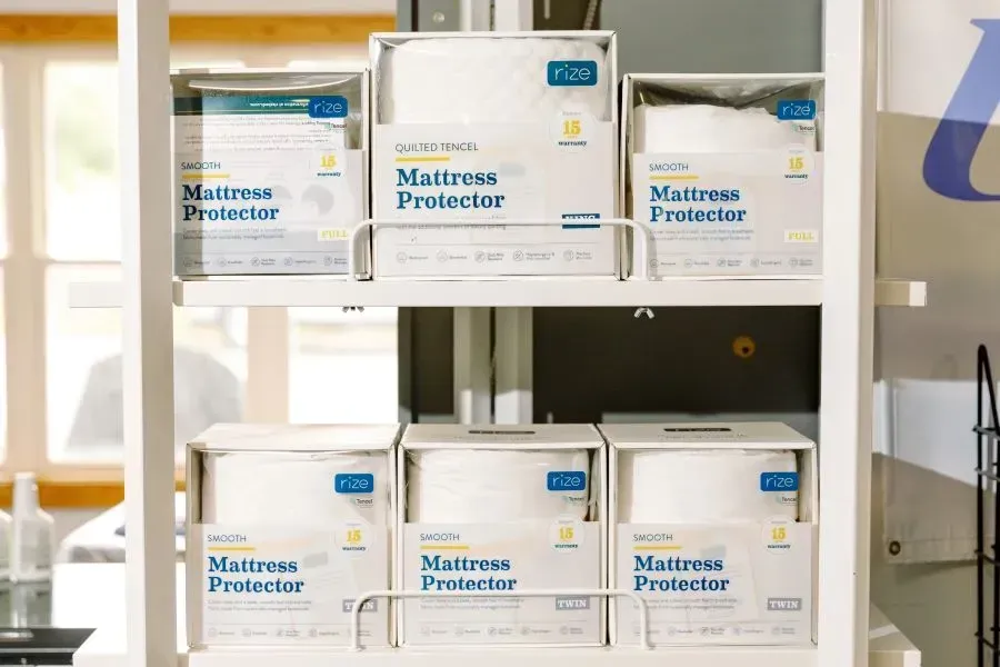 Boxes of mattress protectors are stacked on top of each other on a shelf.