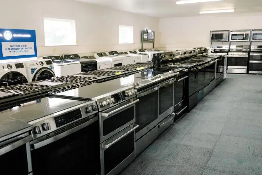 A large room filled with lots of appliances including a washing machine , stove , oven , and microwave.