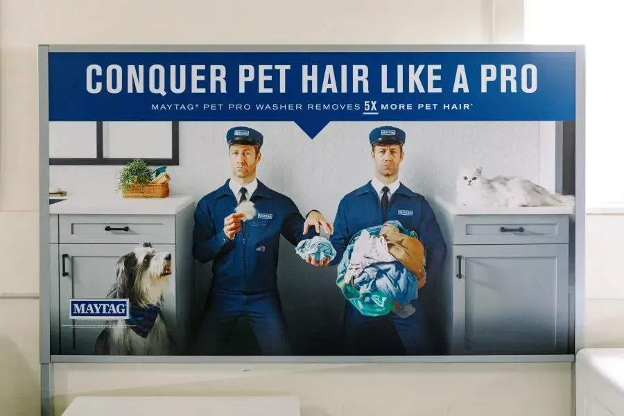 A billboard with two men and a dog on it that says `` conquer pet hair like a pro ''.