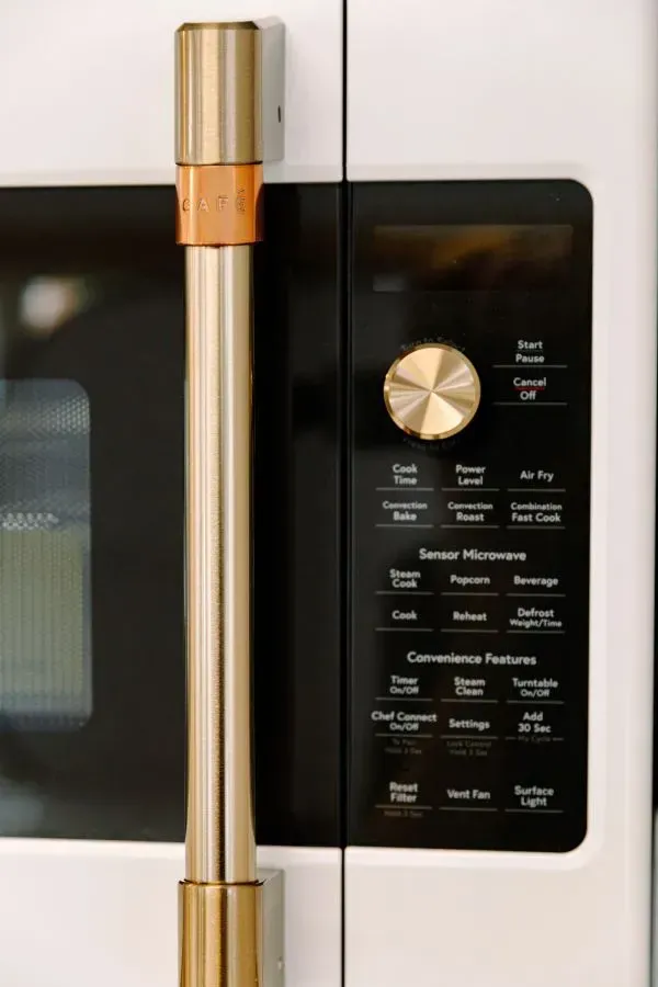 A close up of a microwave oven with a gold handle.