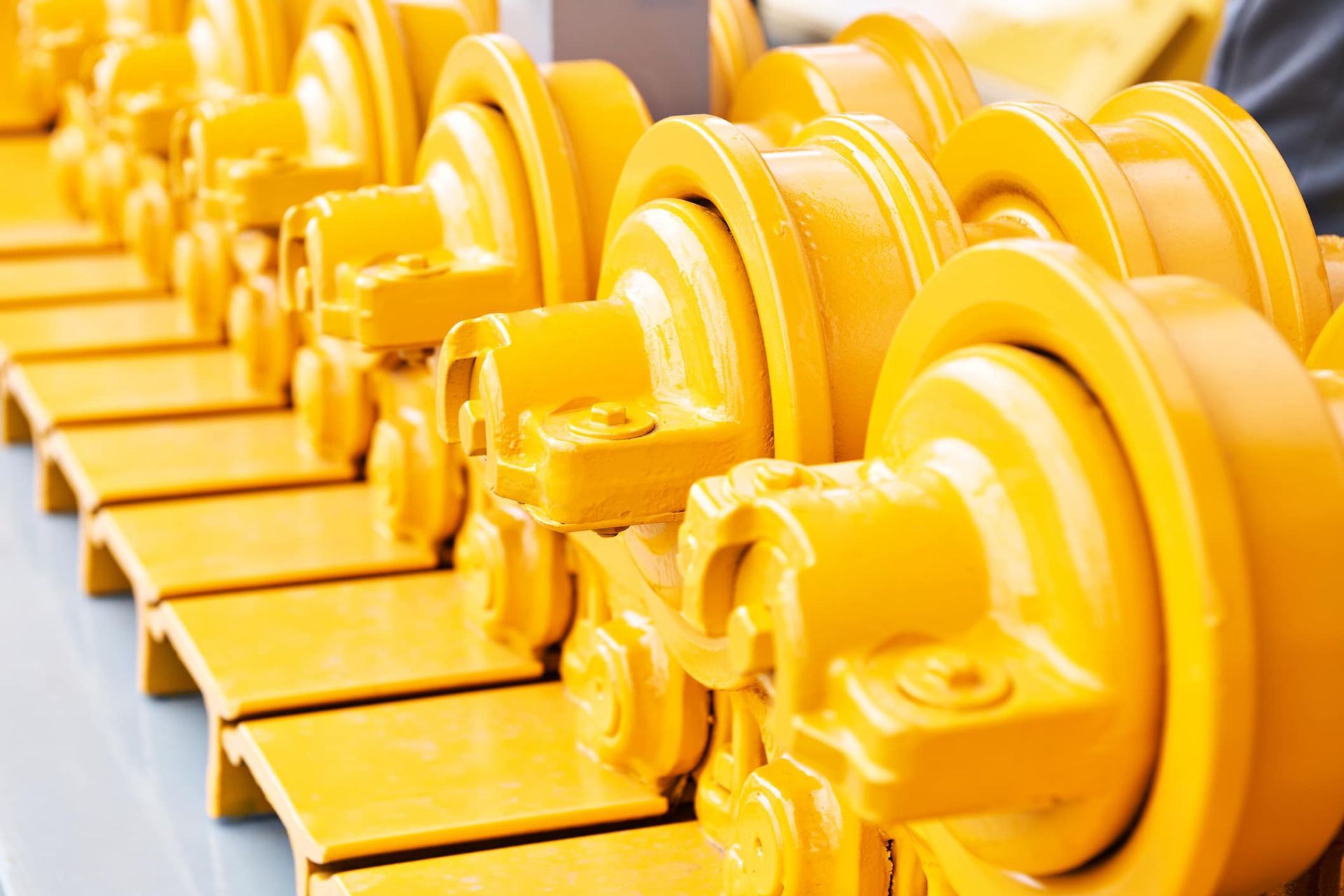 Row of bright yellow industrial machine parts lined up in a workshop